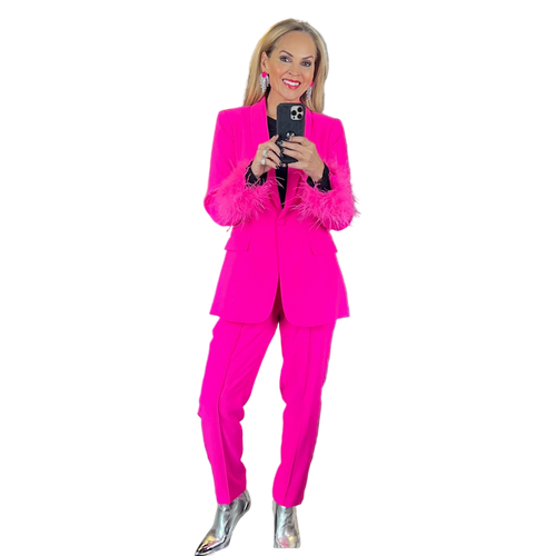 Woman in a hot pink suit with feathered cuffs, silver metallic boots, and statement earrings