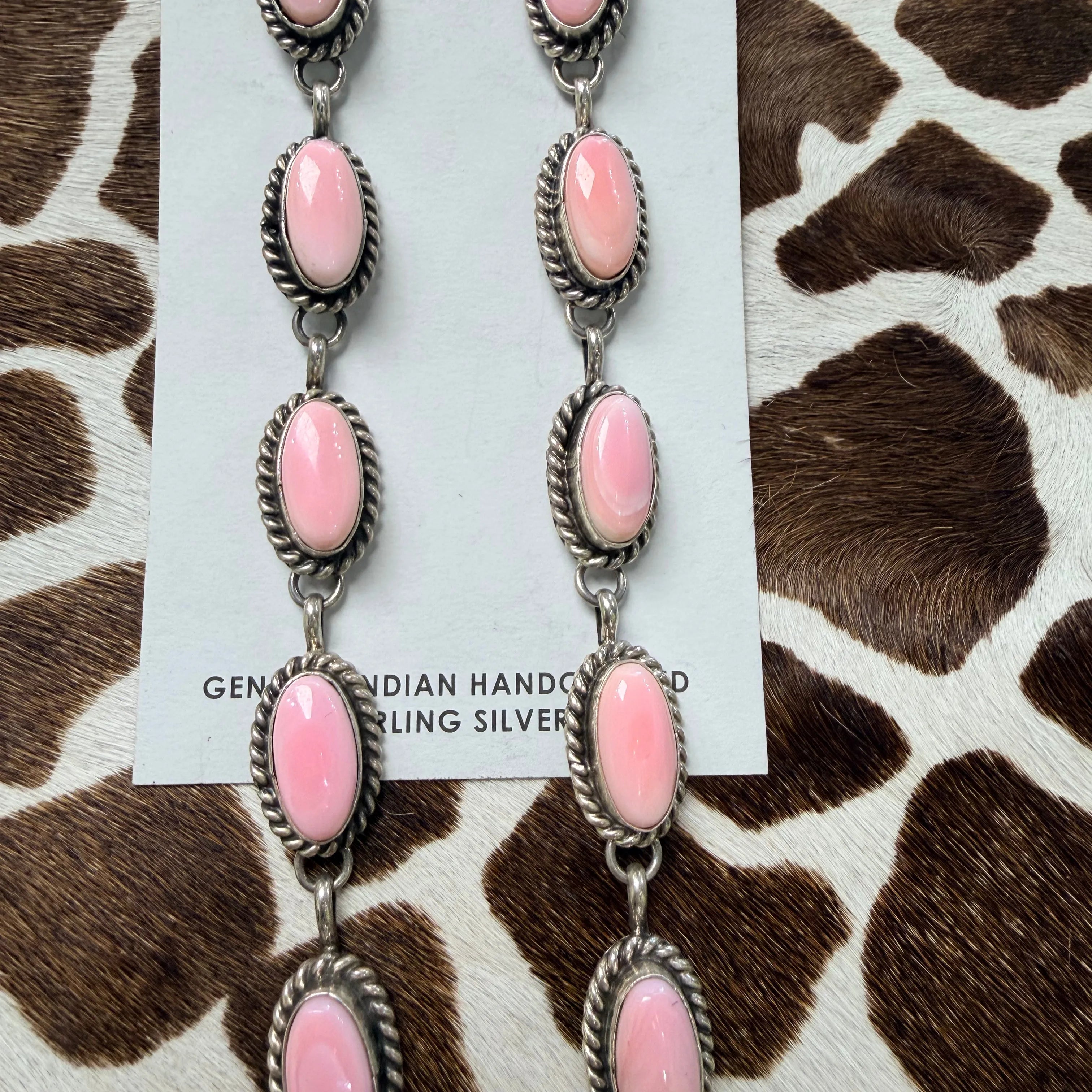 Pink conch shell and sterling silver dangle earrings with rope-twist bezels on a Genuine Indian Handcrafted Sterling Silver card