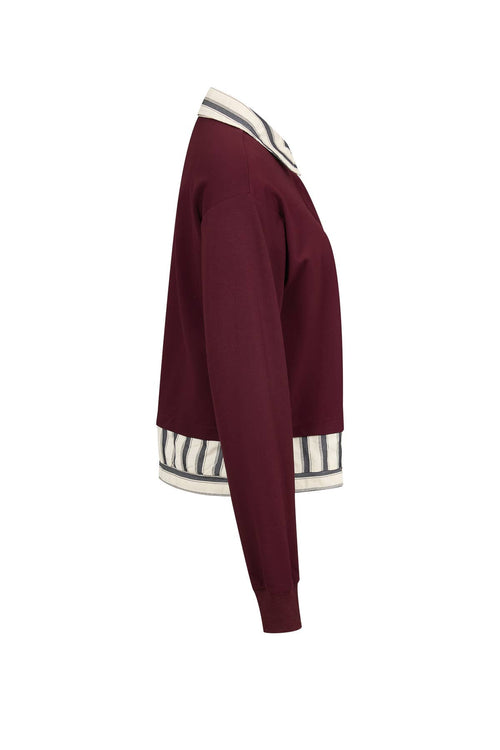 Side view of the Anette burgundy sweatshirt showing the striped layered hem